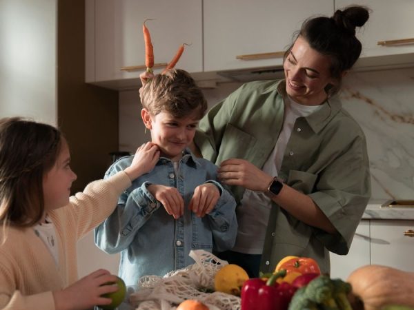 Mother and children have fun unpacking vegetables in the kitchen.